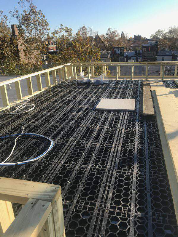 Photo of the beginning stages of building a rooftop deck with wooden railings and StoneDeks SilcaGrates.