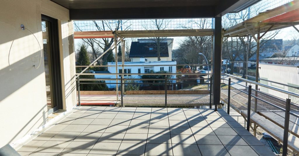 An in-the-process residential balcony renovation. The newly paved balcony is surrounded by scaffolding.