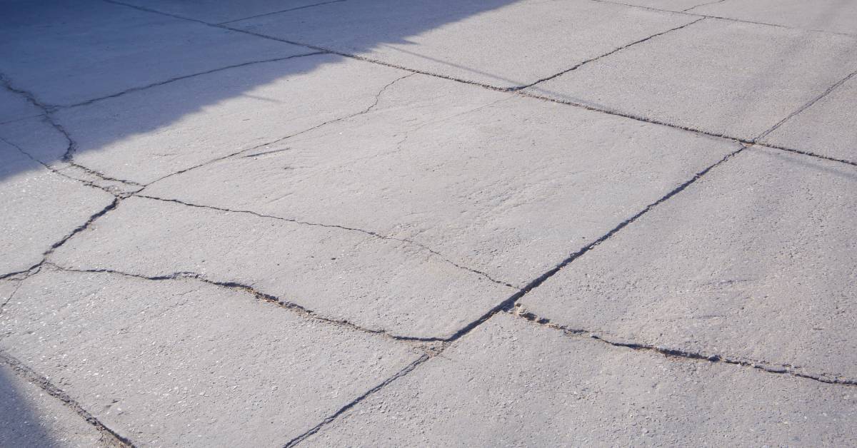 A close-up of an outdoor stone deck with multiple noticeable cracks running throughout the stone pavers.